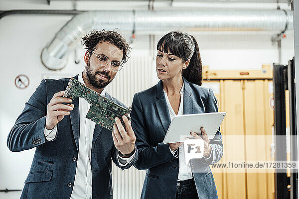 Business colleagues discussing while examining circuit board at industry