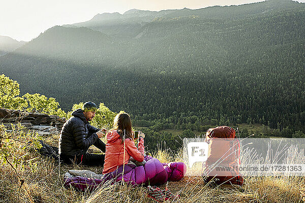 Couple sitting looking at view while drinking coffee in forest