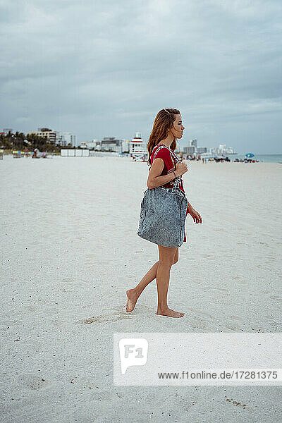 Frau mit Handtasche auf Sand am Strand