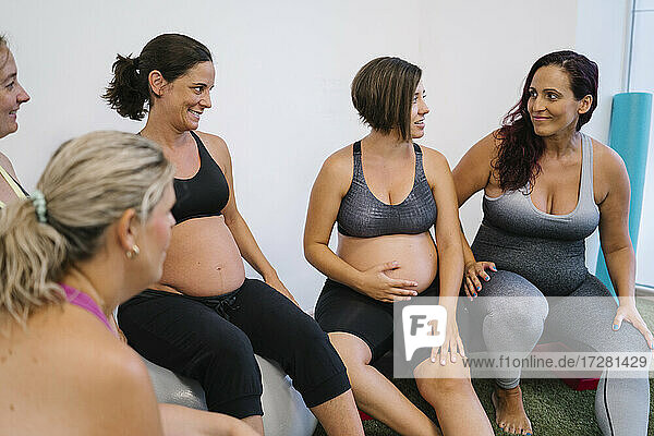 Gruppe schwangerer Frauen  die sich im Yogastudio miteinander unterhalten