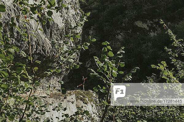 Female trekker hiking by rocky cliff on sunny day