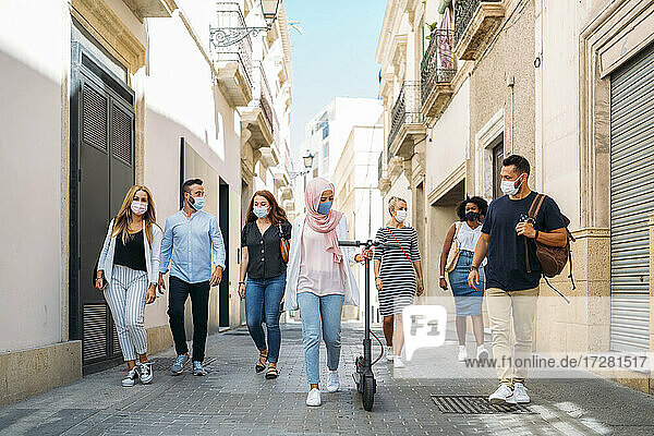 Freunde mit Gesichtsmasken gehen auf der Straße in der Stadt
