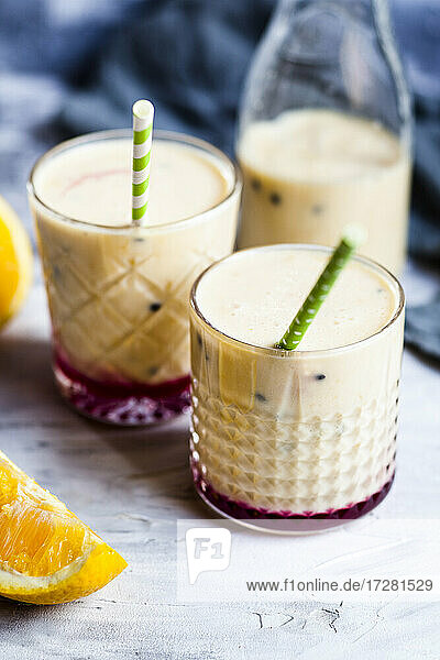 Glasses of fresh fruit smoothie with oranges  bananas  yogurt and grenadine