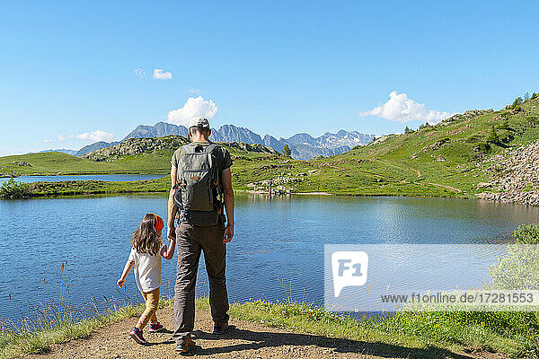 Vater und Tochter betrachten die Aussicht bei einem Spaziergang auf dem Gehweg an einem sonnigen Tag