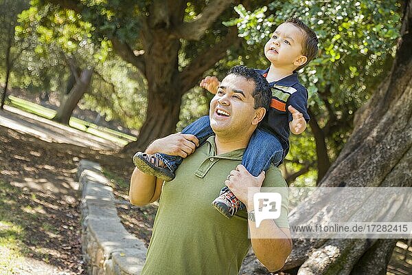 Happy mixed-race son enjoys a piggy back ride in the park with dad