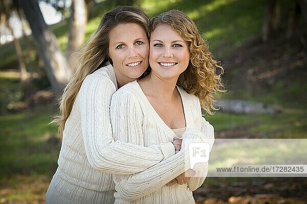 Pretty mother and daughter portrait hugging in the park on a fall day
