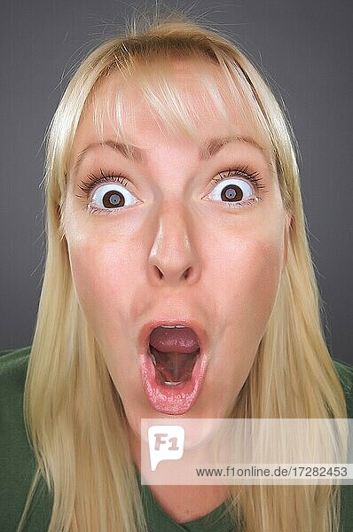 Shocked blond woman with funny face against a grey background