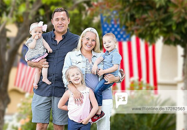 Happy young caucasian family in front of houses with american flags