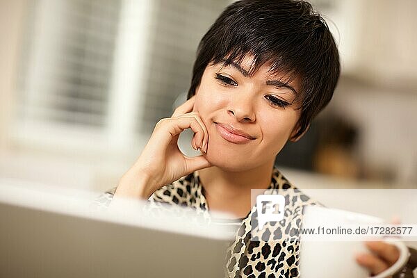 Pretty smiling mixed-race young woman using laptop computer