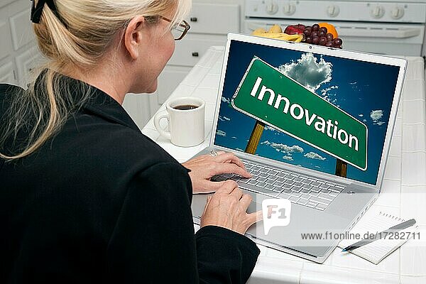 Frau in der Küche mit Laptop mit Innovation Straßenschild auf dem Bildschirm. Bildschirm kann leicht für Ihre eigene Nachricht oder Bild verwendet werden
