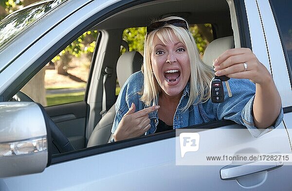 Attraktive glückliche Frau im neuen Auto mit Schlüssel