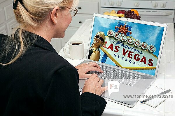 Woman in kitchen using laptop to research A las vegas trip. screen can be easily used for your own message or picture. picture on screen is my copyright as well