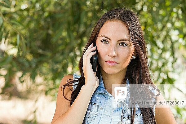 Unglückliche gemischtrassige junge Frau  die draußen mit dem Handy telefoniert