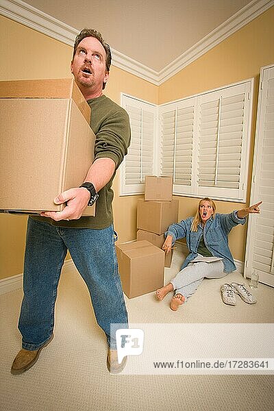 Gestresster Mann bewegt Kisten für anspruchsvolle Frau umgeben von anderen Kisten