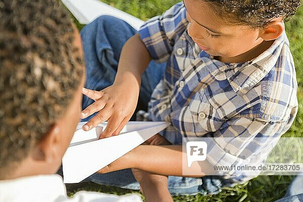 Happy mixed-race father and son playing with paper airplanes in the park