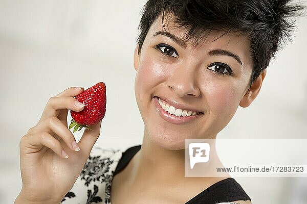 Hübsche hispanische Frau hält Erdbeere in ihrer Küche