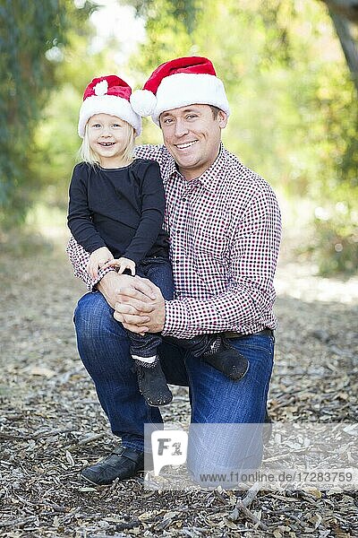 Portrait of father and daughter wearing santa hats outdoors