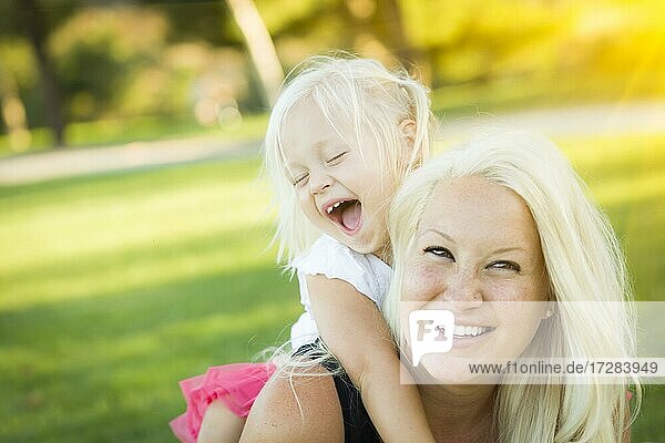 Pretty mother and little girl having fun together in the grass