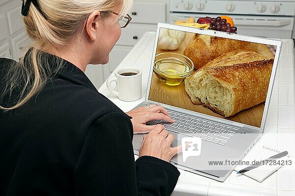 Frau in der Küche mit Laptop zu recherchieren Kochen und Rezepte. Bildschirm kann leicht für Ihre eigene Nachricht oder Bild verwendet werden
