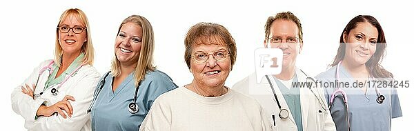 Lächelnde ältere Frau mit Ärzten und Krankenschwestern hinter vor einem weißen Hintergrund