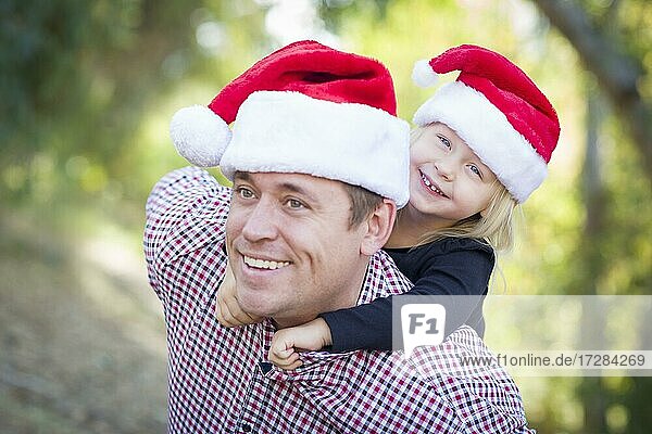 Glücklicher Vater und Tochter mit Spaß tragen santa Hüte im Freien