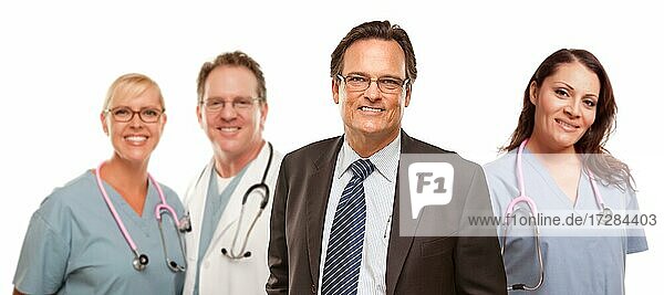 Lächelnde Geschäftsmann in Suite und Krawatte  während männliche und weibliche Ärzte und Krankenschwestern stehen hinter vor einem weißen Hintergrund