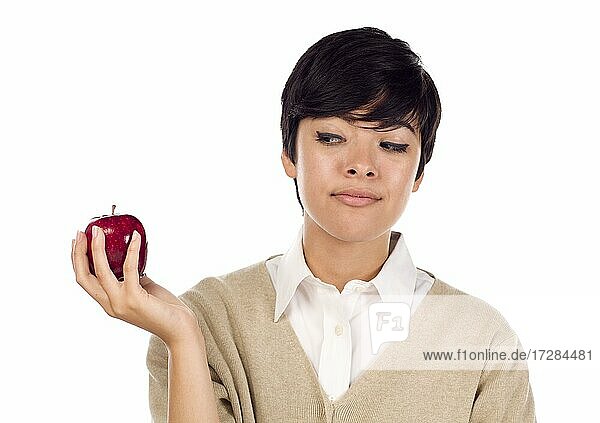 Hübsche hispanische junge adultes Weibchen schaut auf Apfel in der Hand vor einem weißen Hintergrund