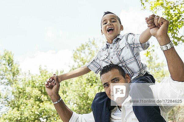 Hispanic Vater und Sohn haben Spaß zusammen Reiten auf Papas Rücken im Park