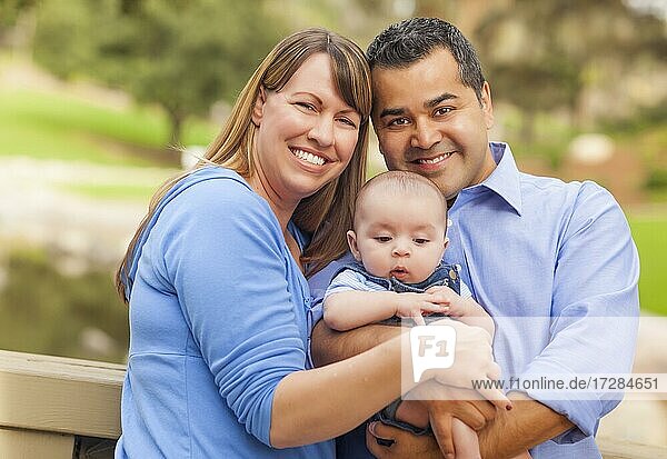 Attractive happy mixed-race young family posing for A portrait outside in the park