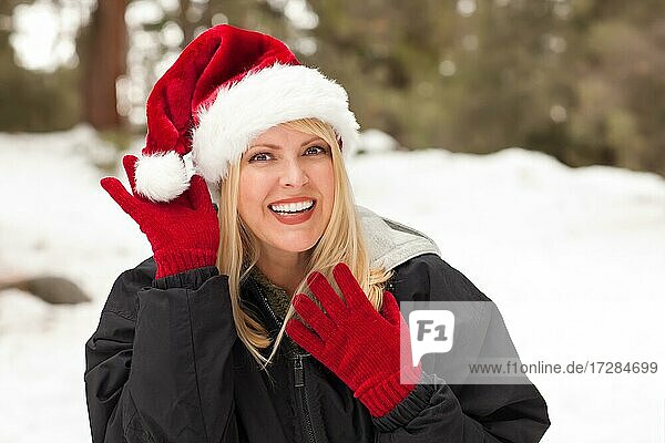 Attraktive Weihnachtsmannmütze tragende blonde Frau  die Spaß im Schnee an einem Wintertag hat