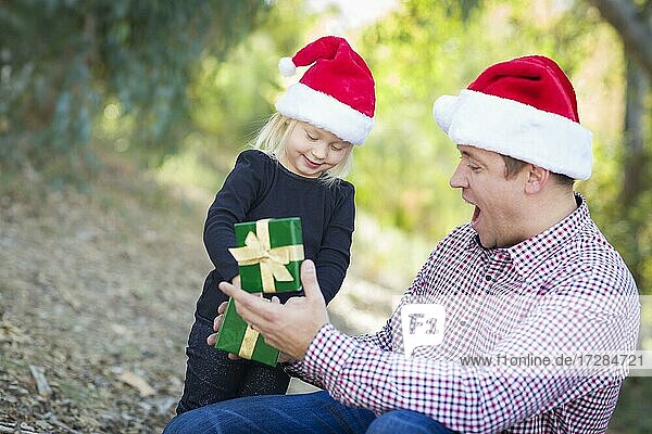 Glücklicher Vater gibt junge Tochter ein Weihnachtsgeschenk im Freien