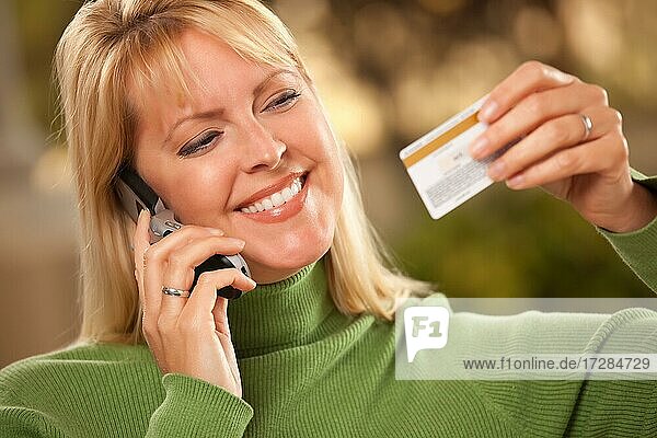 Cheerful smiling woman using her phone with credit card in hand