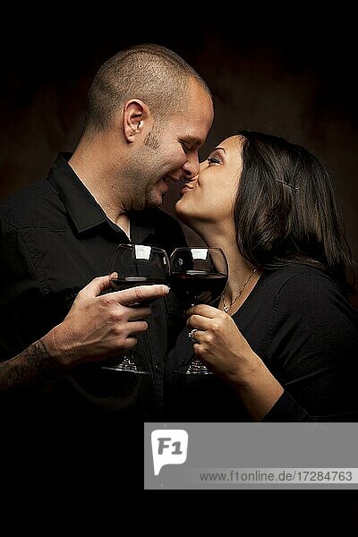 Happy young mixed-race couple holding wine glasses against A black background