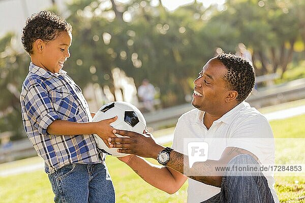 Afroamerikanischer Vater übergibt seinem gemischtrassigen Sohn im Park einen neuen Fußball