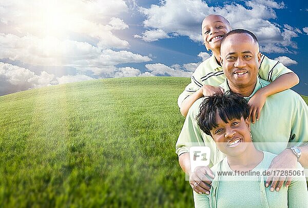 Happy african american family over clouds  sky and arched horizon of grass field