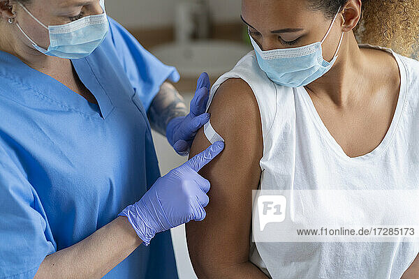 Krankenschwester beim Anlegen eines Verbandes am Arm eines Patienten in einer medizinischen Klinik