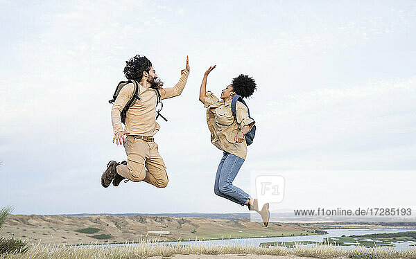 Mid adult couple giving high-five while jumping
