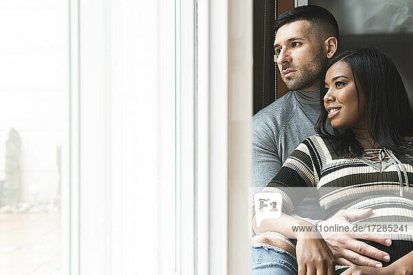 Mid adult couple looking away through window at home