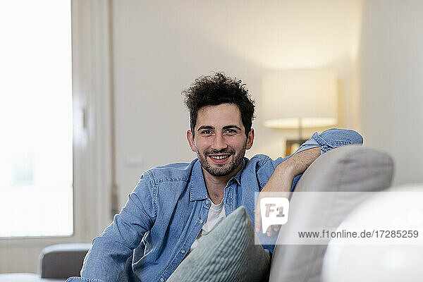 Smiling mid adult man sitting on sofa at home