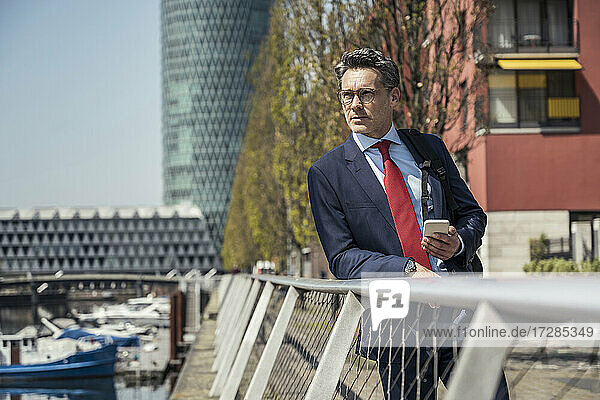Male professional with mobile phone leaning on railing