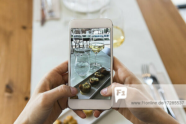 Junge Frau fotografiert Essen mit ihrem Smartphone in einem Restaurant