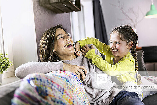Daughter playing with mother while sitting in living room