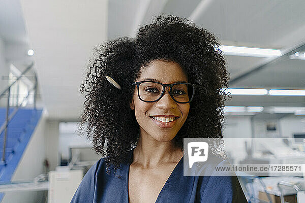 Lächelnde Geschäftsfrau mit krausem Haar in der Industrie