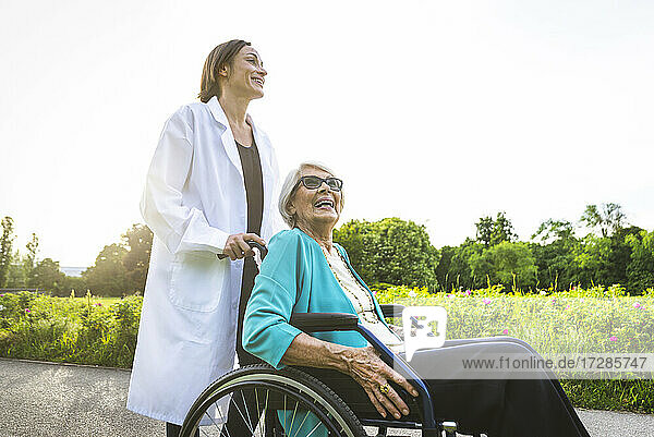 Lächelnde Seniorin mit Hausmeister im öffentlichen Park