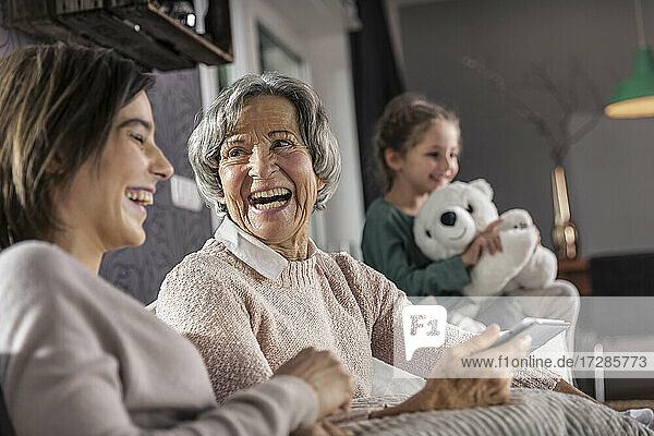 Lächelnde Mutter  die ihre Tochter mit ihrer Enkelin im Hintergrund anschaut