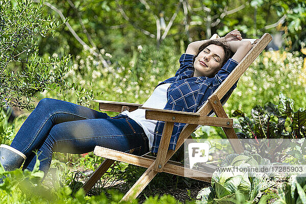 Junge Frau schläft auf einem Stuhl im Bio-Gemüsegarten