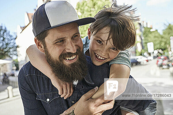 Playful son arm around father on street