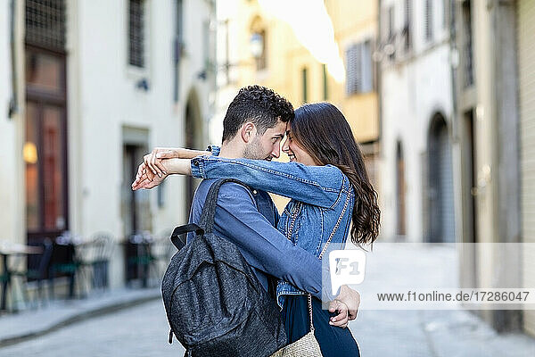 Lächelndes Paar steht mit Gesicht zu Gesicht und Arm um auf der Straße der Stadt