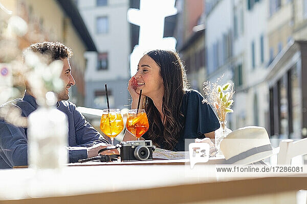 Couple with drinks talking while sitting at sidewalk cafe