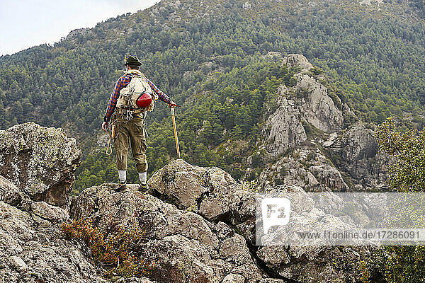 Mid adult male mountaineer looking at view while standing on mountain